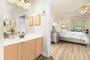 A bedroom with a bed, bedside table, lamp, and window with blinds. - SA Family Retreat Near SeaWorld •Six Flags •Lackland w/ EV Charger, BBQ (San Antonio)