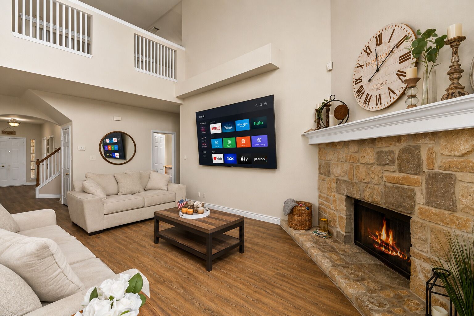 A spacious living room with a fireplace, a mounted TV displaying streaming services, and a clock on the wall.