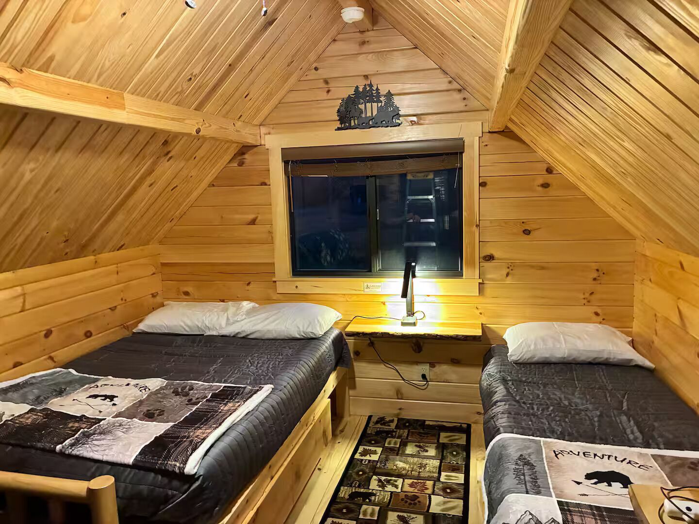 Una cabaña acogedora con dos camas, techo de madera y ventana con vistas.