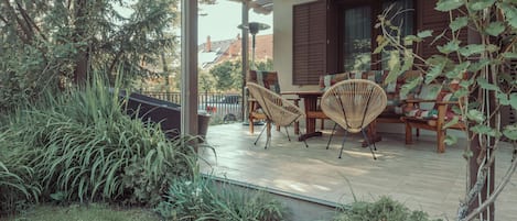 A covered patio with wicker furniture, a table, and chairs.