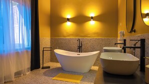 Ein Badezimmer mit einer freistehenden Badewanne, einem großen Waschbecken und einem Spiegel.