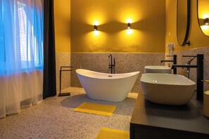 Een badkamer met een vrijstaand bad, een ruime wastafel en een spiegel.
