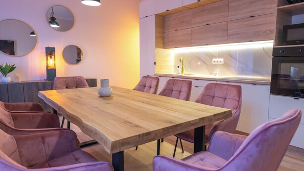 Ein moderner Essbereich mit einem Holztisch und violetten Polsterstühlen.