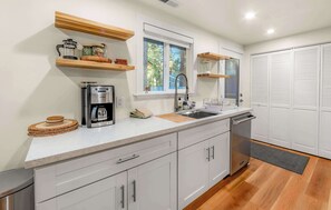 A modern kitchen with a built-in coffee maker, a sink, and wooden shelves. - Tanglewood Tahoe Retreat (South Lake Tahoe)