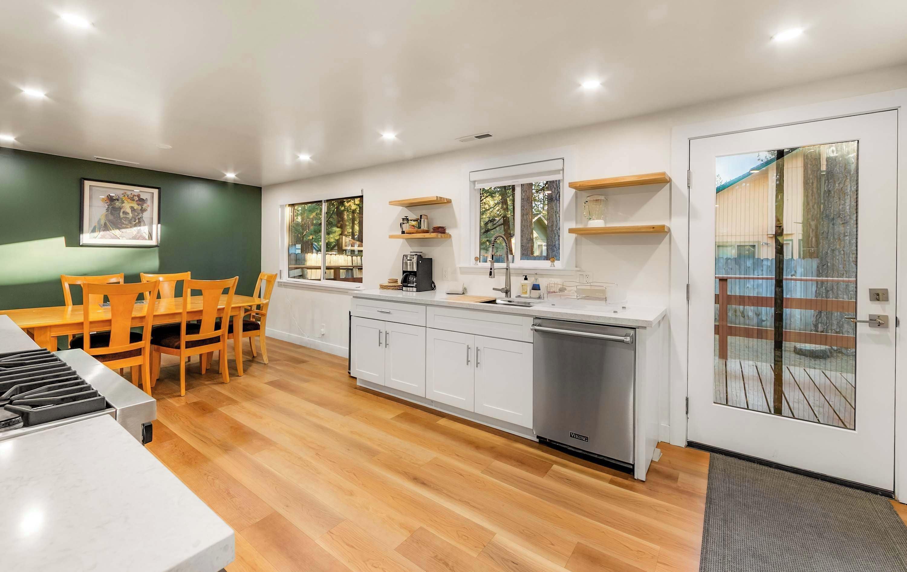 A modern kitchen with white cabinets, a built-in dishwasher, and wooden flooring.
