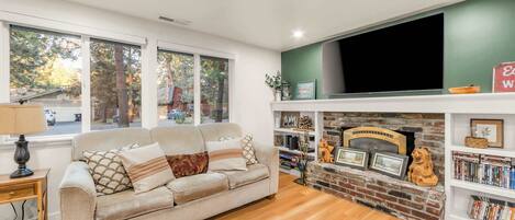A living room with a sofa, a fireplace, a bookshelf, and a television.