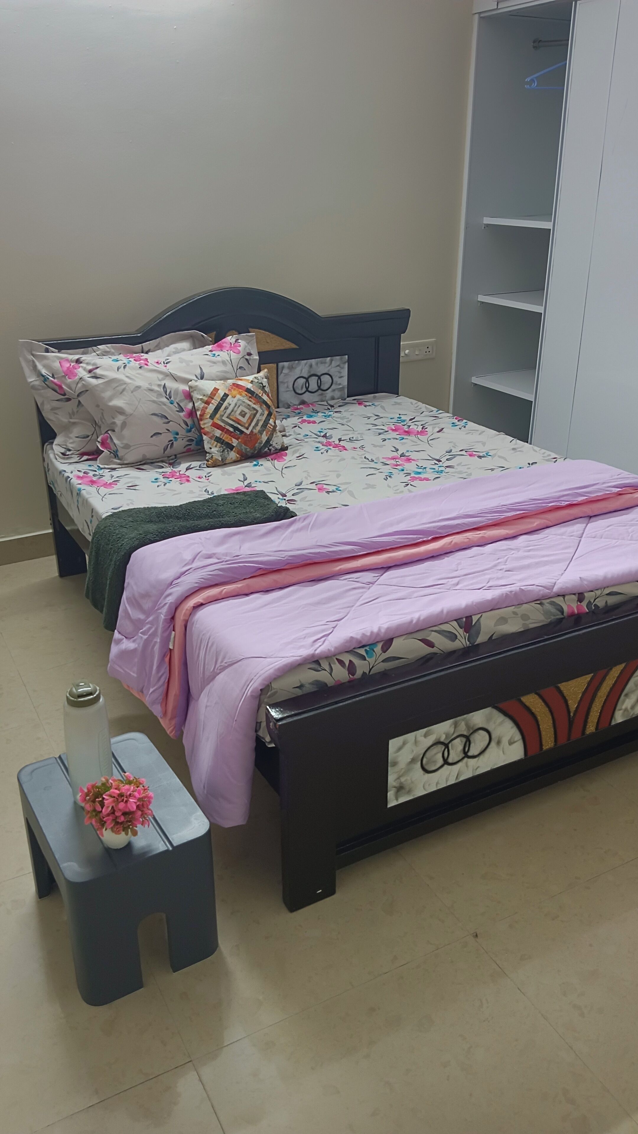 Une chambre à coucher avec un lit, une table de chevet ornée d’un vase et une armoire.