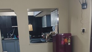 Uma cozinha com geladeira, mesa de jantar e vista para o cômodo adjacente.
