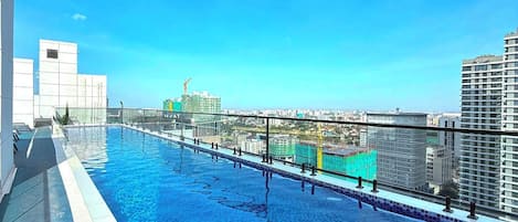 A rooftop swimming pool with a clear view of the cityscape and construction cranes in the background.