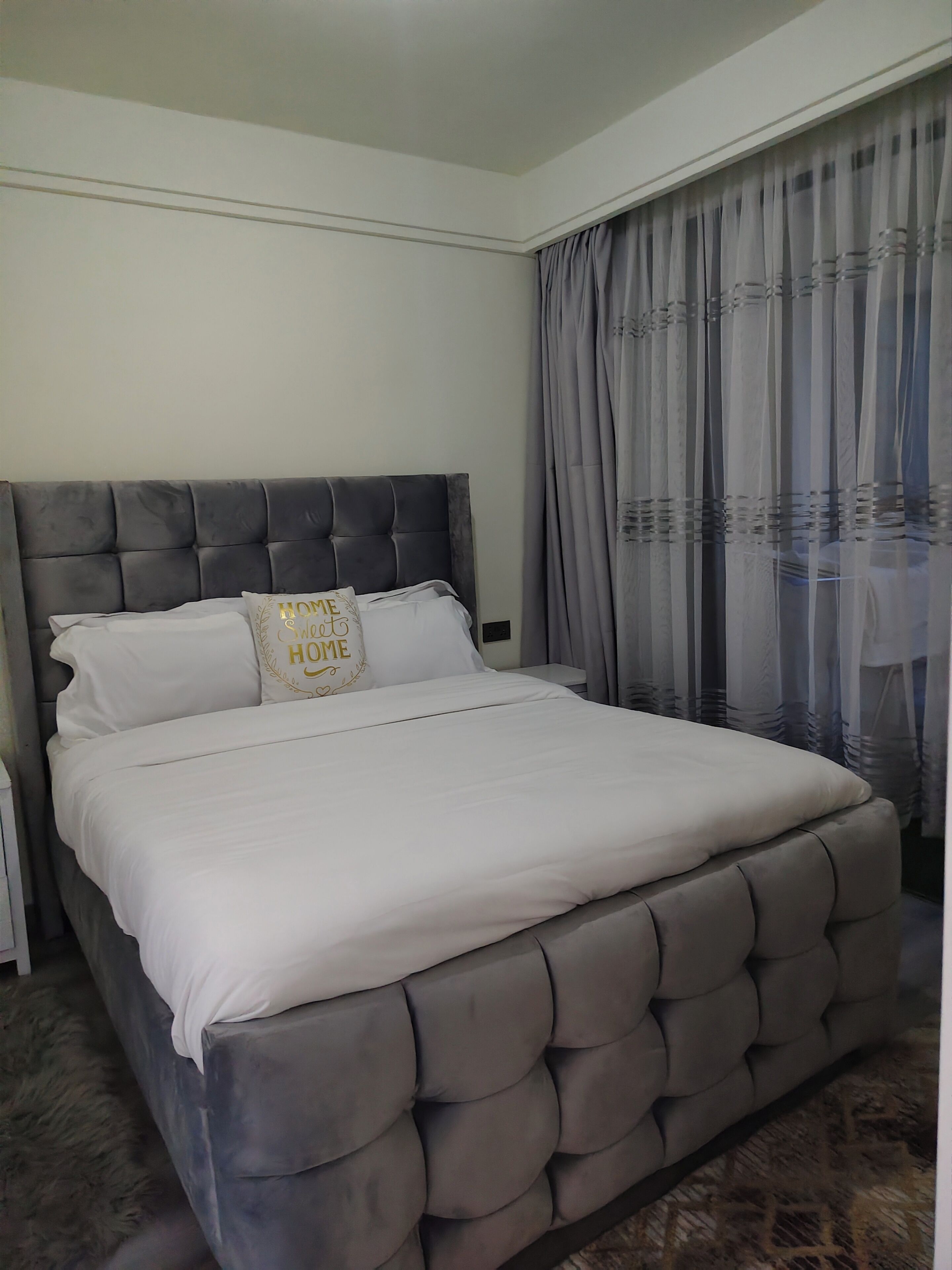 Une chambre à coucher avec un grand lit, une tête de lit et une fenêtre avec des rideaux.