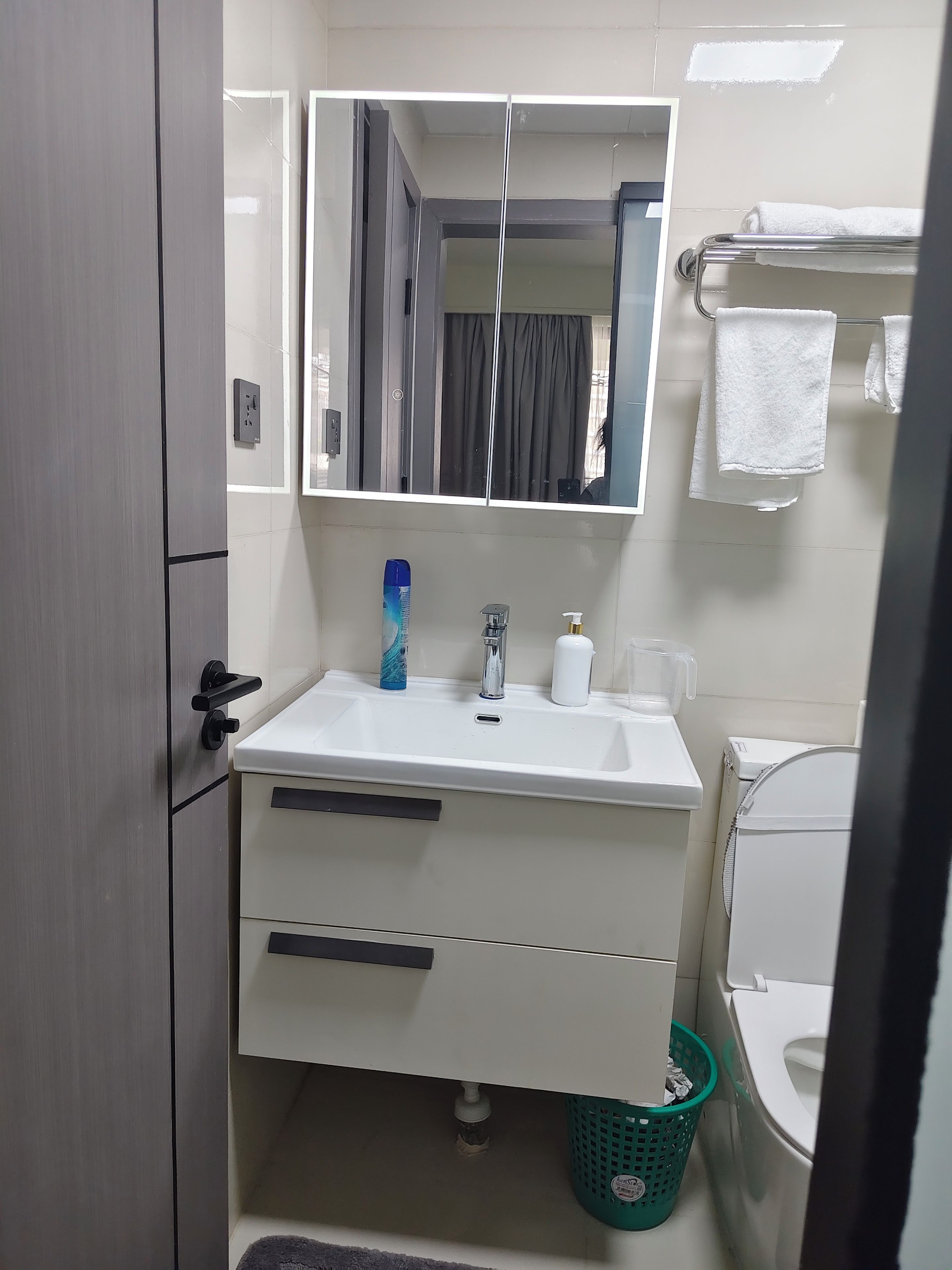 A bathroom with a white sink, a mirror, a towel rack, and a toilet.