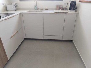 Eine Küche mit weißen Schränken, einem Toaster, einer Kaffeemaschine und einem Spülbecken.