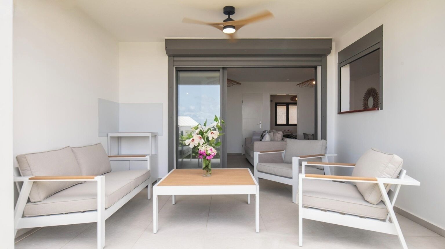 Un salon moderne avec un canapé blanc, une table basse en bois et un ventilateur de plafond.