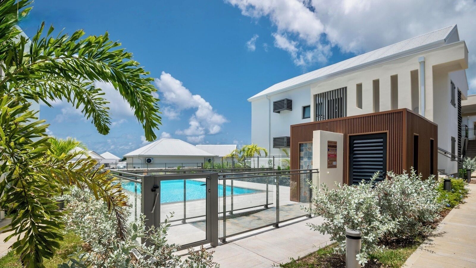 A modern hotel with a swimming pool, a covered area, and a well-maintained garden.