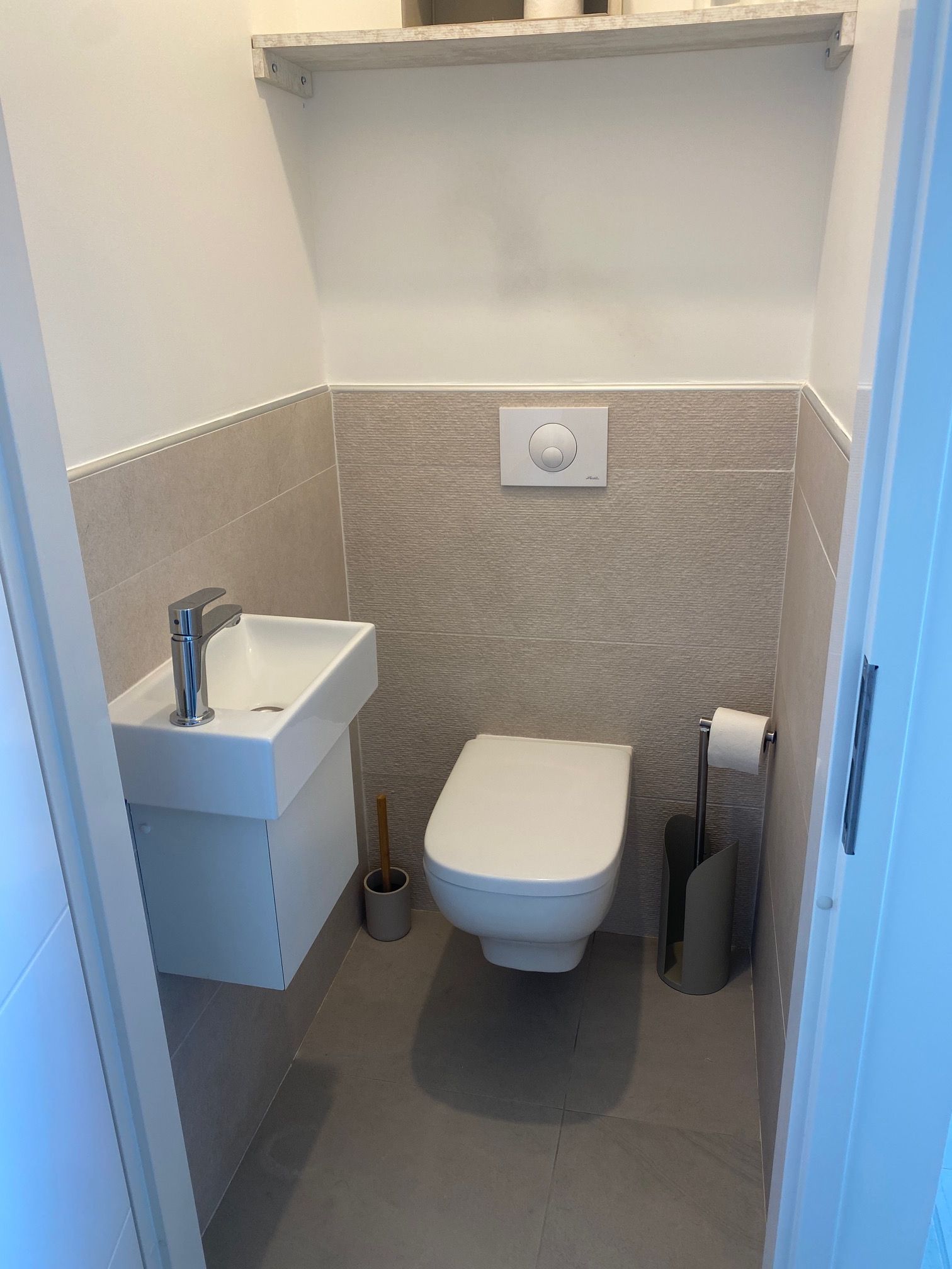 Ein kleines, modernes Badezimmer mit Waschbecken, Toilette und Handtuchhalter.