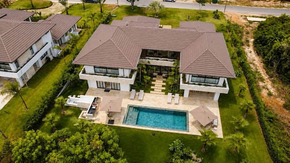 A modern two-story house with a swimming pool, surrounded by well-maintained lawns and palm trees. - El Bosque II Casa de Campo (La Romana)
