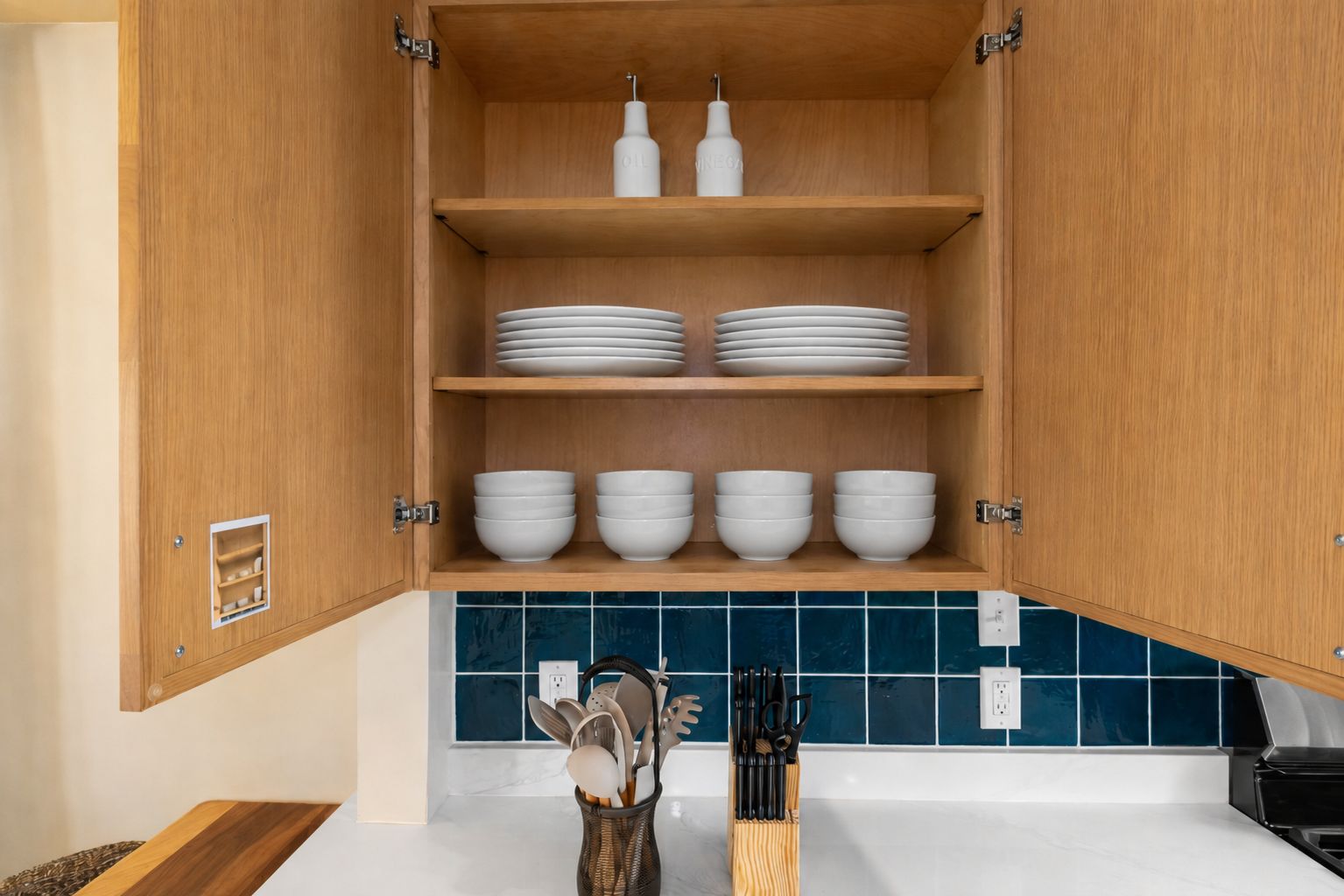 A kitchen with wooden cabinets, white plates, bowls, and a knife block.
