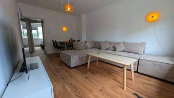 Ein modernes Wohnzimmer mit Sofa, Couchtisch und Fernseher auf einem Schrank.
