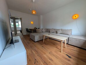 A modern living room with a sofa, a coffee table, and a TV on a stand.