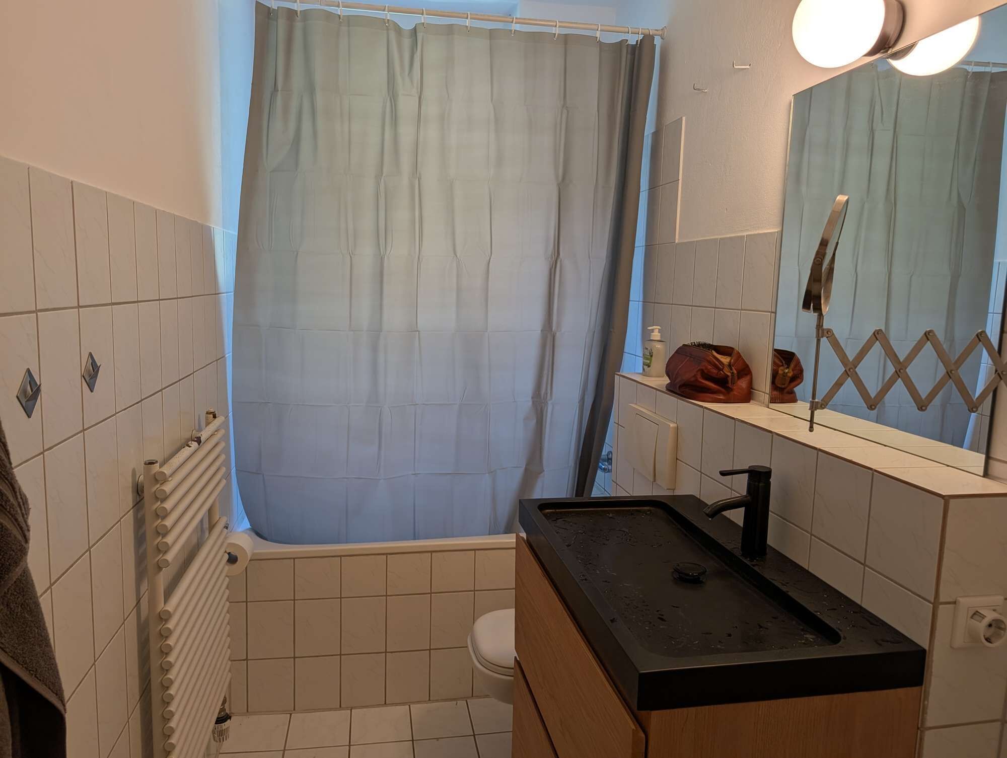 Ein Badezimmer mit Badewanne, Toilette, Waschbecken mit Spiegel und Handtuchhalter.