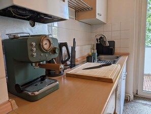 A kitchen with a coffee machine, a cutting board, and a sink. - Stylish 1-Bedroom Apartment with Balcony | Close to the City Centre (Hannover)