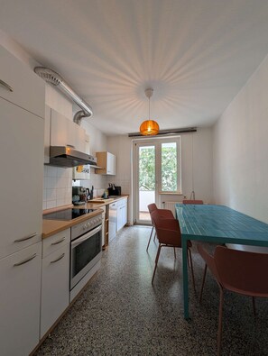 A kitchen with white cabinets, a stove, and a table with chairs.