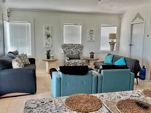 A living room with a sofa set, a patterned armchair, and a coffee table with placemats.