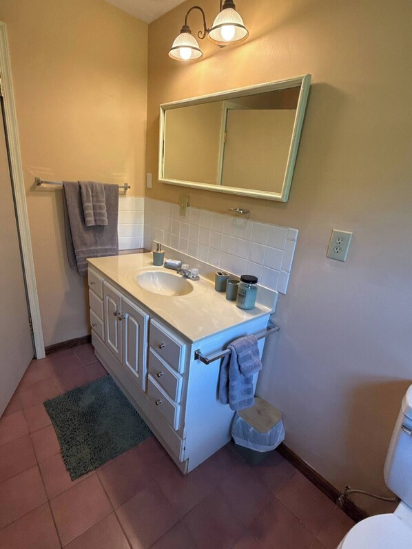 A bathroom with a white sink, mirror, and towel rack.