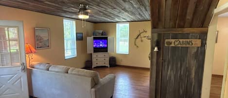 Ein Wohnzimmer mit einer Couch, einem Fernseher und einer Holzbalkendecke.