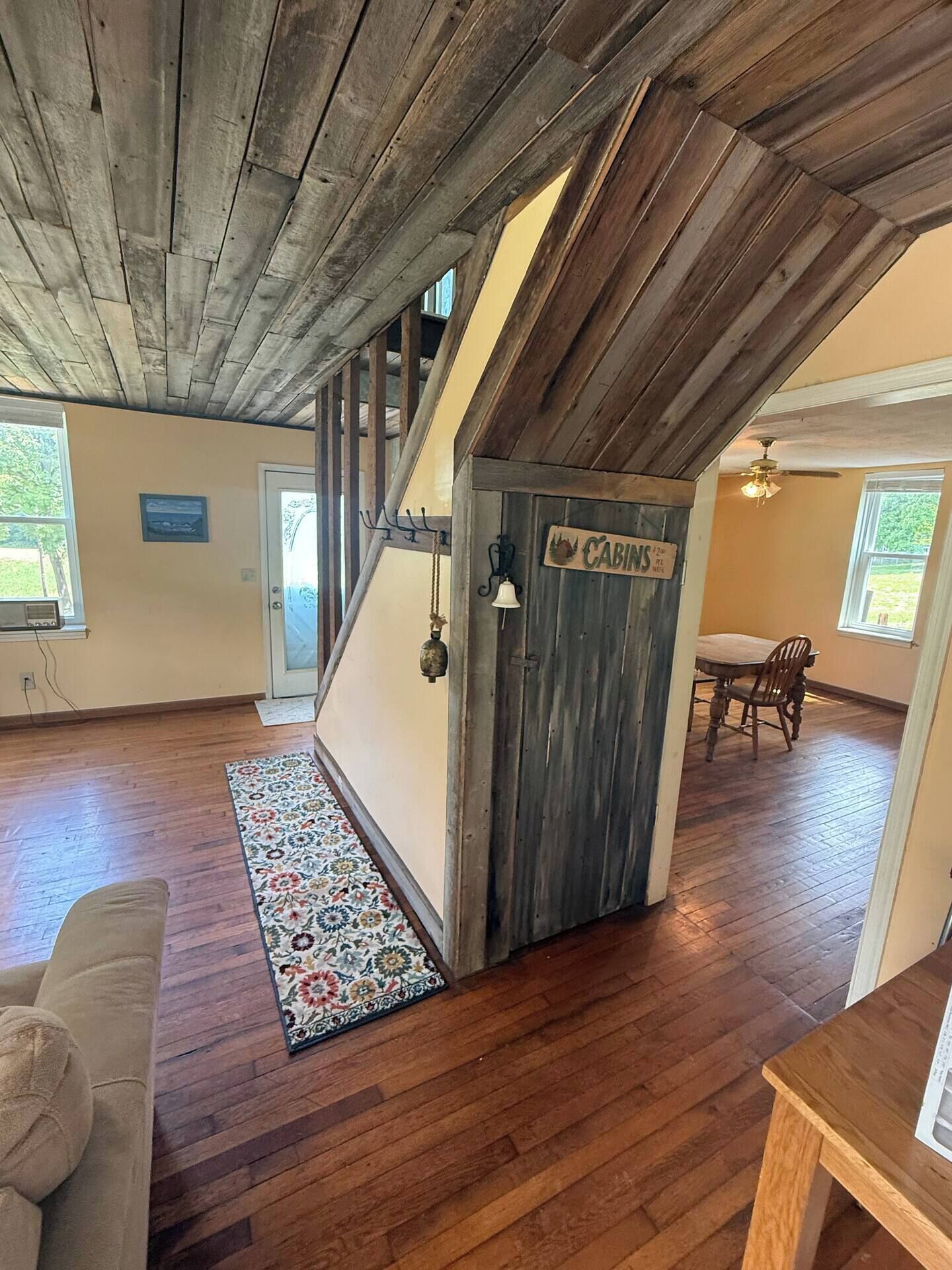 Un intérieur avec un plafond en bois, une porte portant l’inscription « CABINES », un coin repas avec une table et des chaises, et un tapis à motifs.