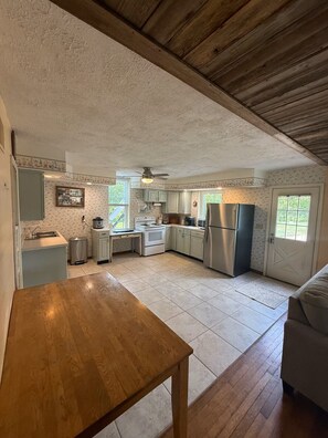 Una cocina amplia con una mesa de madera, un refrigerador y una ventana.