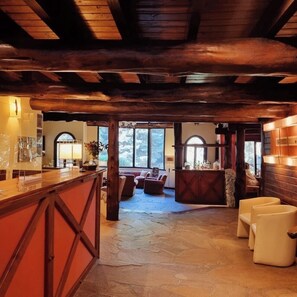 A rustic interior with a stone floor, wooden beams, a bar area, and seating. - Hosteria Altos Los Pioneros  (Villa La Angostura)