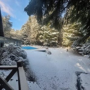 A snow-covered outdoor area with a pool, surrounded by trees.