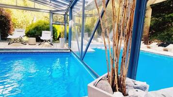 Una piscina cubierta, una piscina al aire libre, tumbonas
