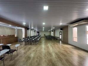 A conference room with rows of chairs, a podium, and a wooden panel wall.