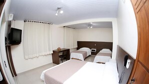 Una habitación de hotel con cama, escritorio, silla, televisor y teléfono.