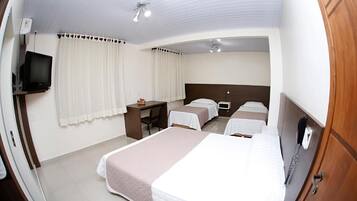 A hotel room with a bed, a desk, a chair, a television, and a telephone.
