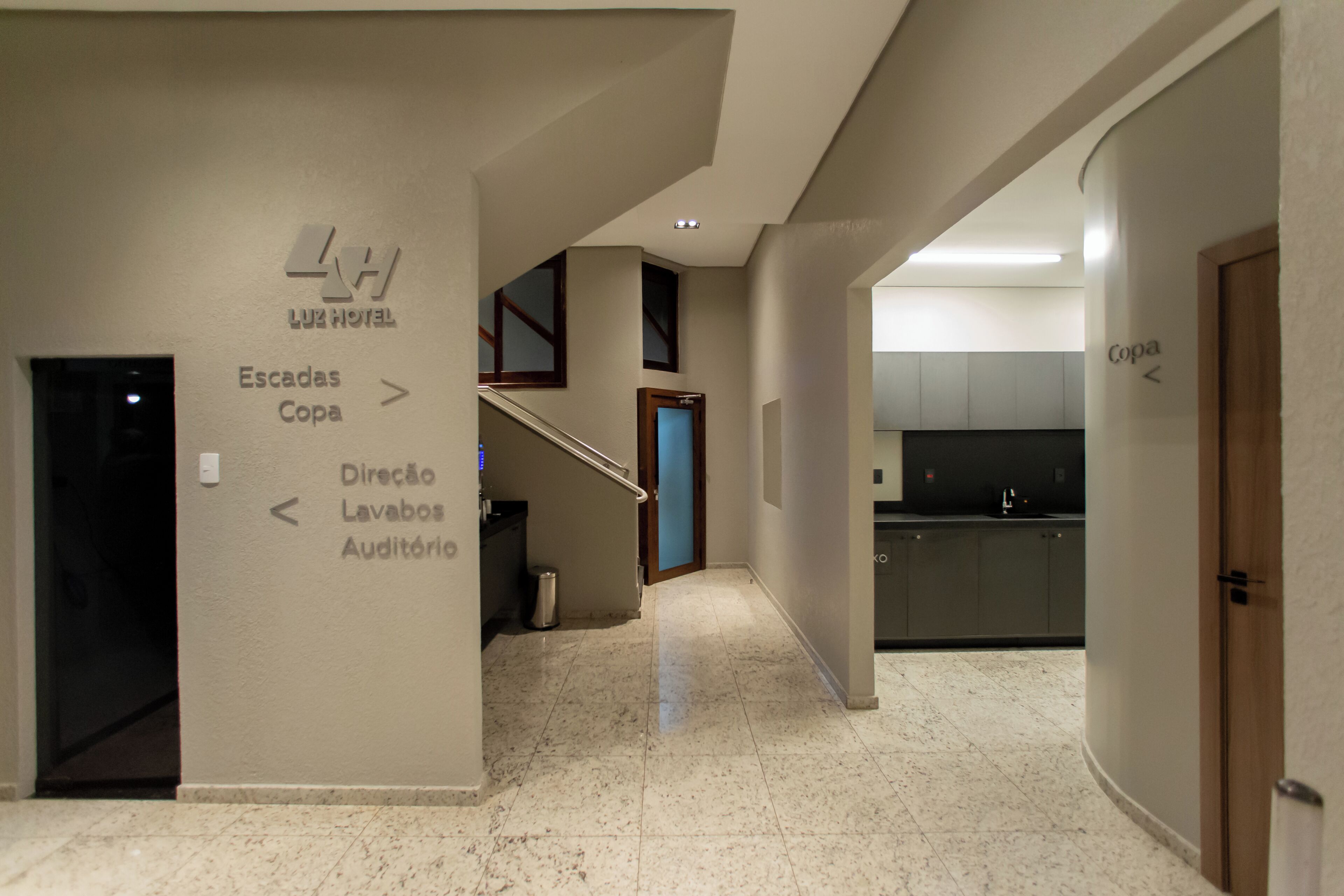 A hotel corridor with directional signs to the lobby, bathrooms, and an auditorium.