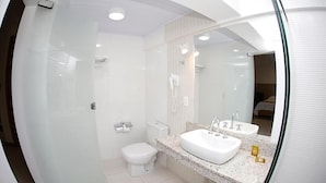 Un baño moderno con cabina de ducha de vidrio, inodoro blanco y tocador doble.