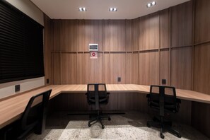 A conference room with a long table, two chairs, and a wall-mounted alarm panel.