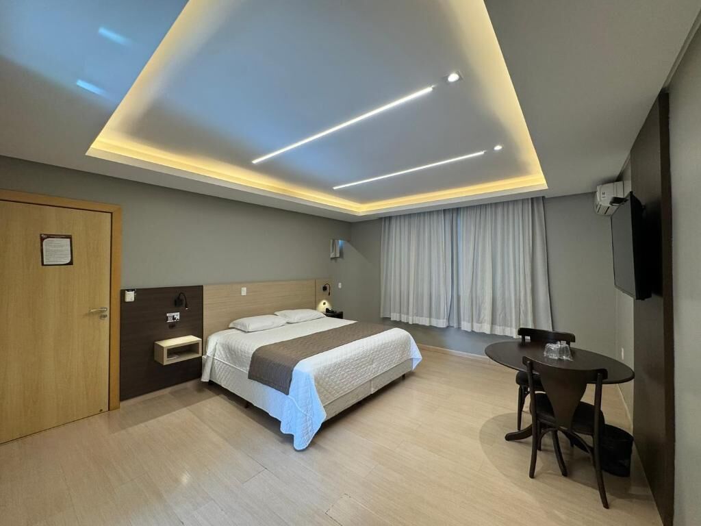 Una habitación de hotel con cama, mesita de noche, escritorio y silla.