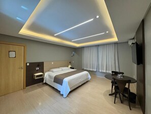 Una habitación de hotel con cama, mesita de noche, escritorio y silla.