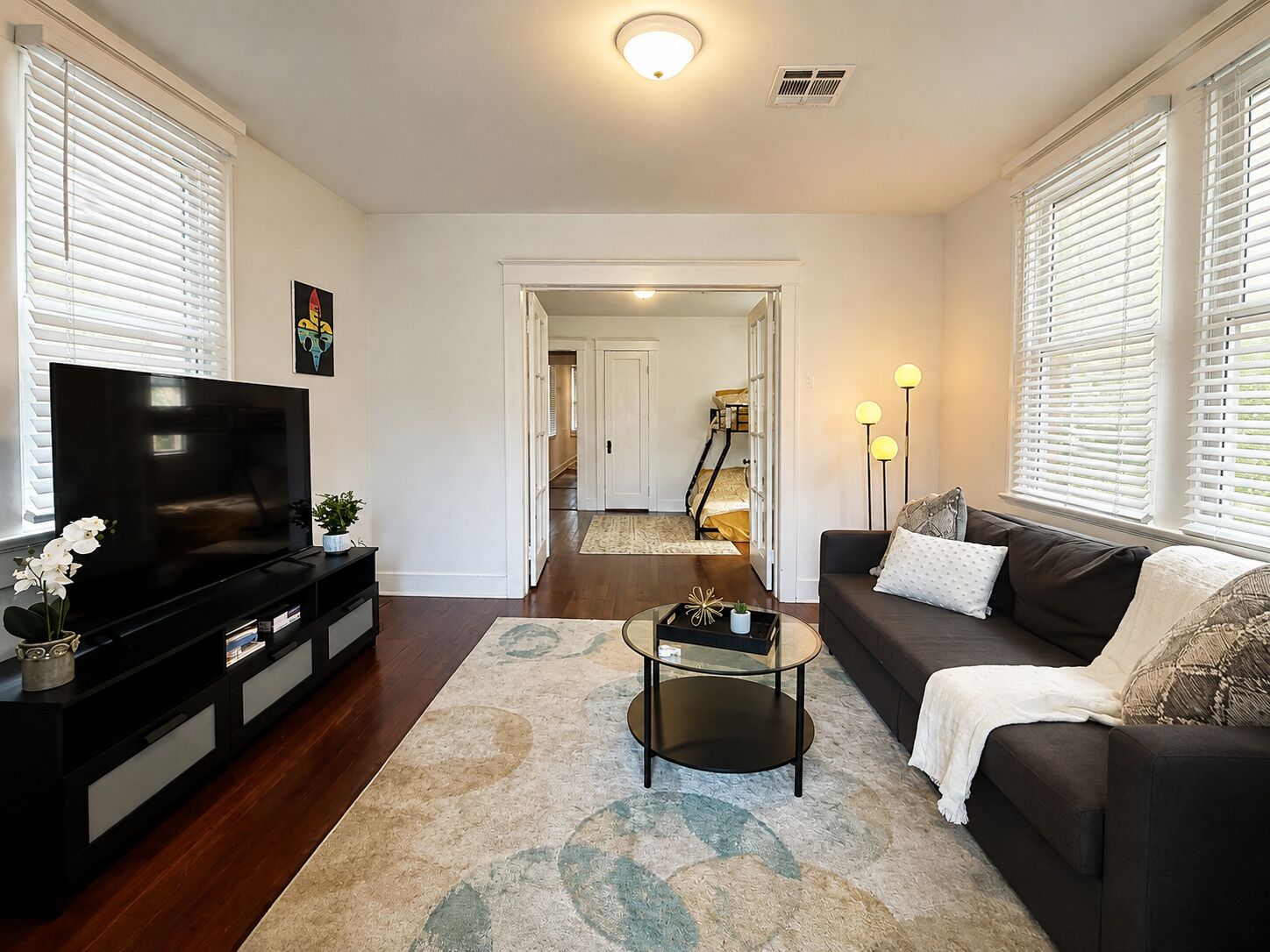 A living room with a TV, sofa, coffee table, and a hallway leading to a staircase.
