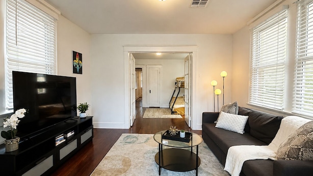 A living room with a TV, sofa, coffee table, and a hallway leading to a staircase.
