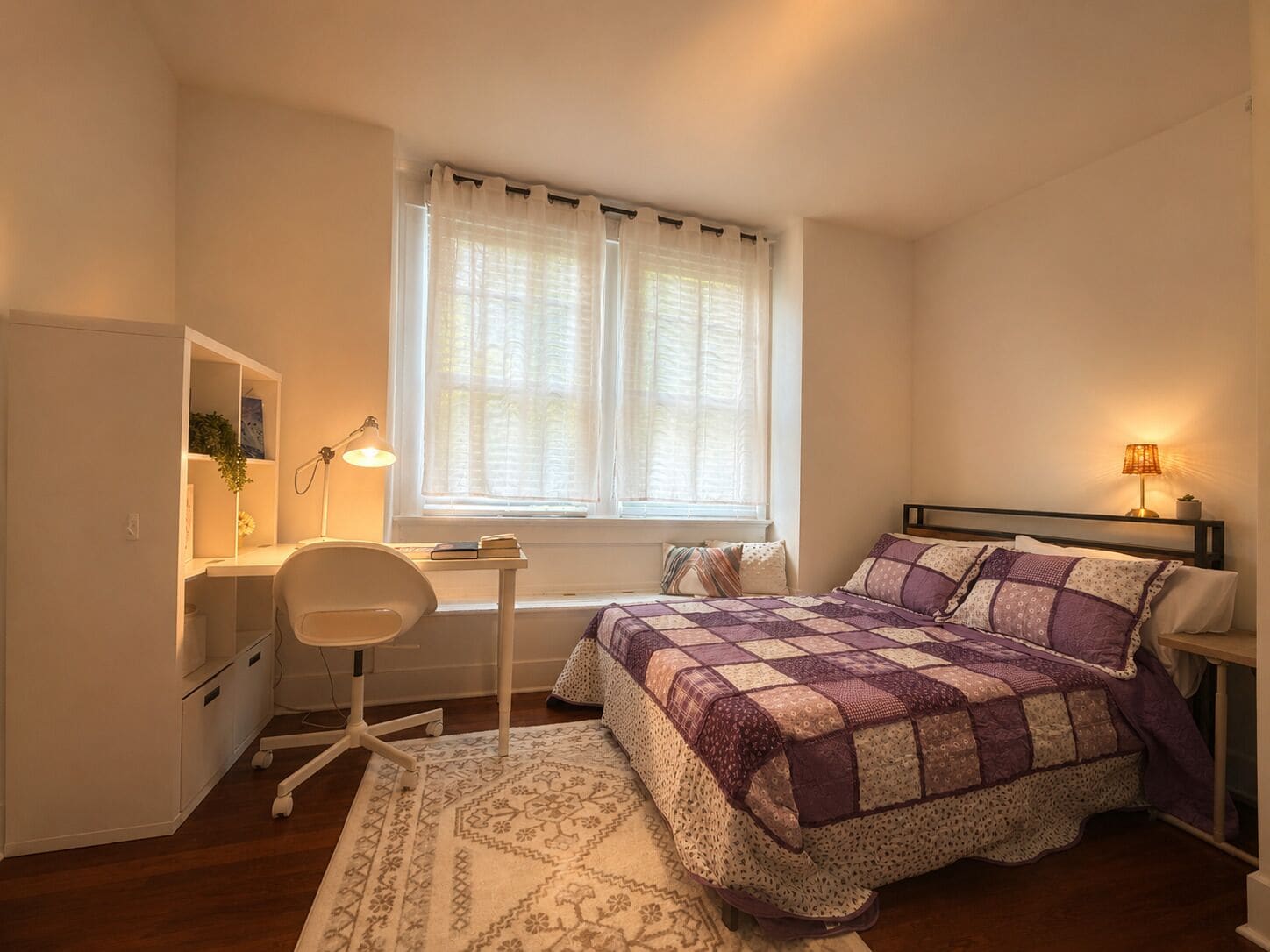 A bedroom with a bed, desk, chair, and a window with curtains.