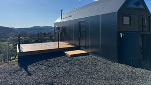 Un edificio moderno con techo inclinado, terraza de madera y suelo de grava.
