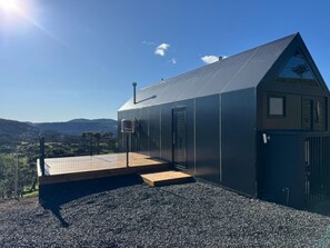 Een modern gebouw met een schuin dak, een houten terras en een grindpad.