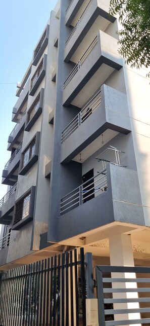 A multi-story building with balconies, a gated entrance, and a clear sky. - Fantastic 3-bedroom apartment in Nashik perfect for your stay  and relaxation. (Nashik)