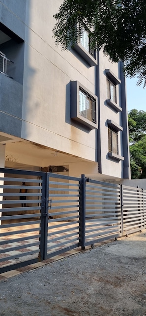 A modern building with a gated entrance, a tiled ground, and a clear sky. - Fantastic 3-bedroom apartment in Nashik perfect for your stay  and relaxation. (Nashik)