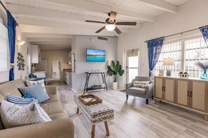 A living room with a sofa, armchair, coffee table, and a television on the wall. - Charming Coastal Studio | Steps to Private Beach | Patio | Casa Mar Resort (Sarasota)